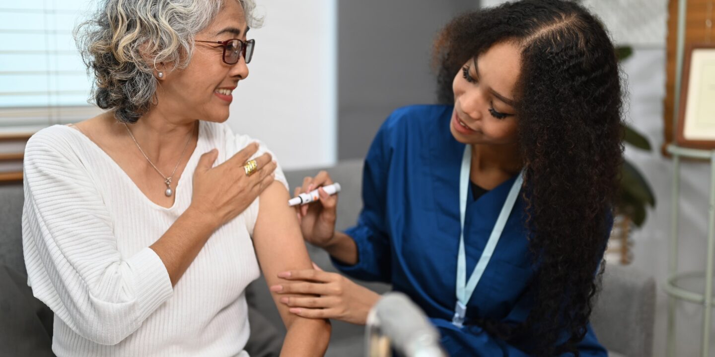 Doctor injecting diabetes treatment into upper arm of diabetic senior woman.