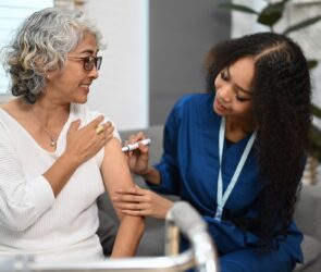 Doctor injecting diabetes treatment into upper arm of diabetic senior woman.