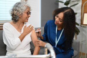 Doctor injecting diabetes treatment into upper arm of diabetic senior woman.