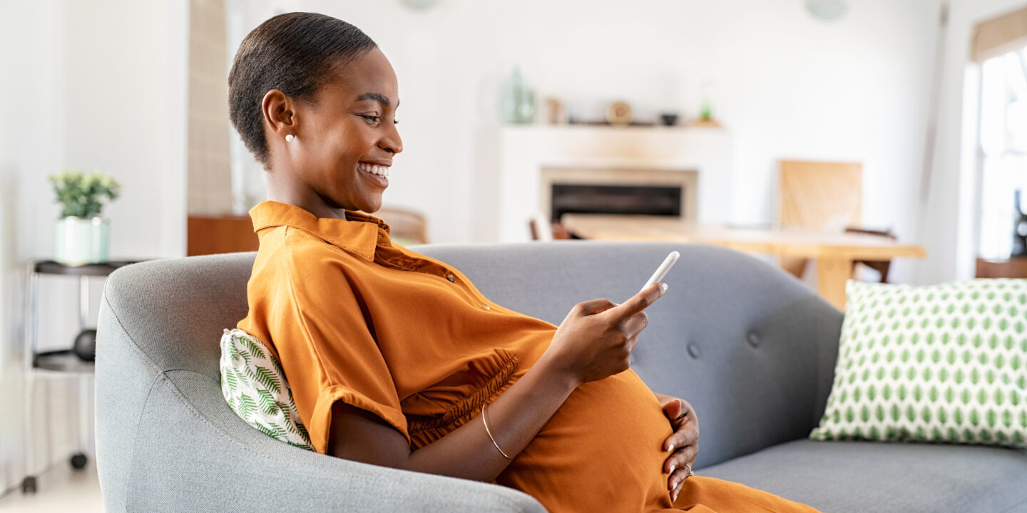 Pregnant african woman using smartphone at home