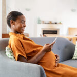 Pregnant african woman using smartphone at home