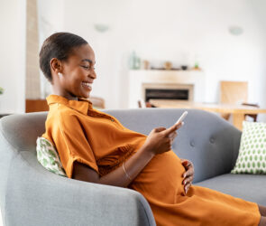 Pregnant african woman using smartphone at home